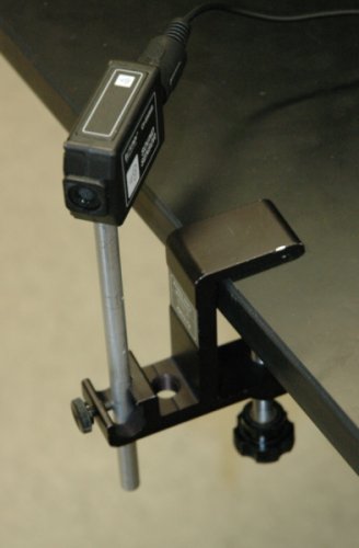 Image of the sound sensor with a 15 cm rod screwed into it and both mounted in the small universal clamp. The clamp is mounted with the long end on the bottom and the bottom of the sound sensor is just barely above the table.